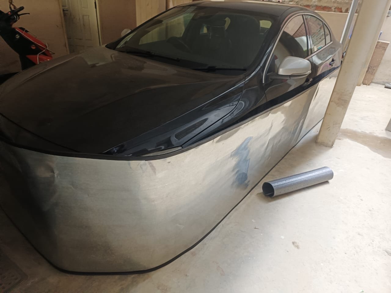 Car-lungi rat protection on grey sedan - aerial top view showing complete 360° GI sheet coverage in industrial shed